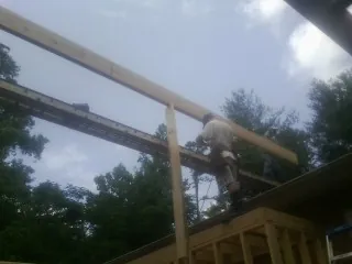 Carpenter setting a ridge beam over a new addition frame — Ice Dam Removal by Roofing Brothers in Bovey