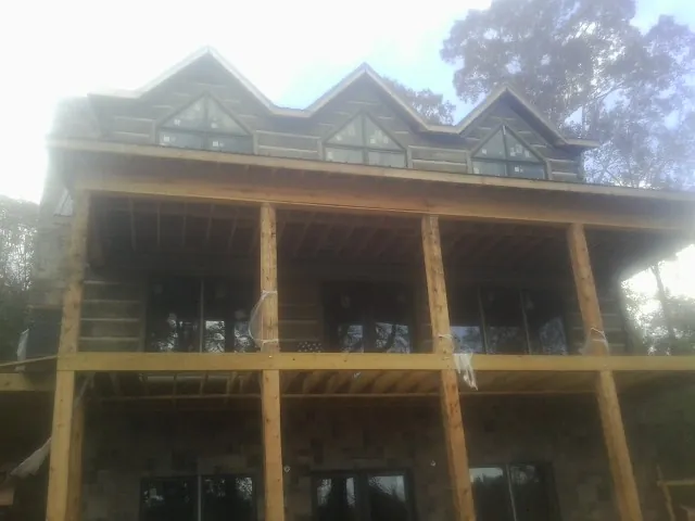 Dormers and porch framing on a large log home under construction — Roof Coating work by our crew in Bovey