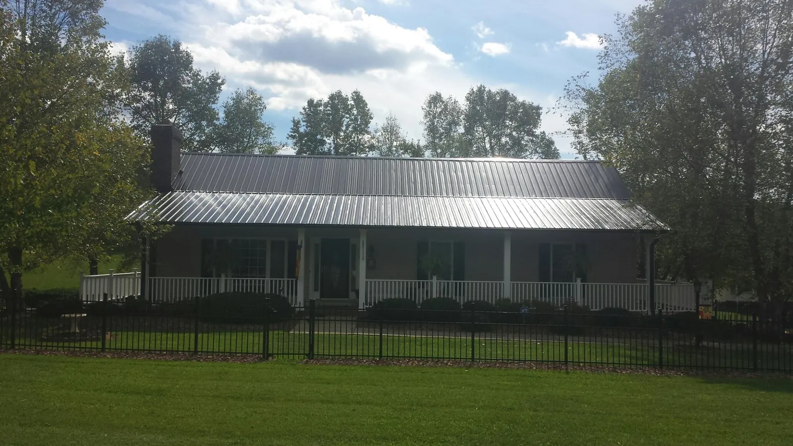 Gray metal roof on a brick ranch with a full width front porch — Gutter Guard Installation work by our crew in Bovey