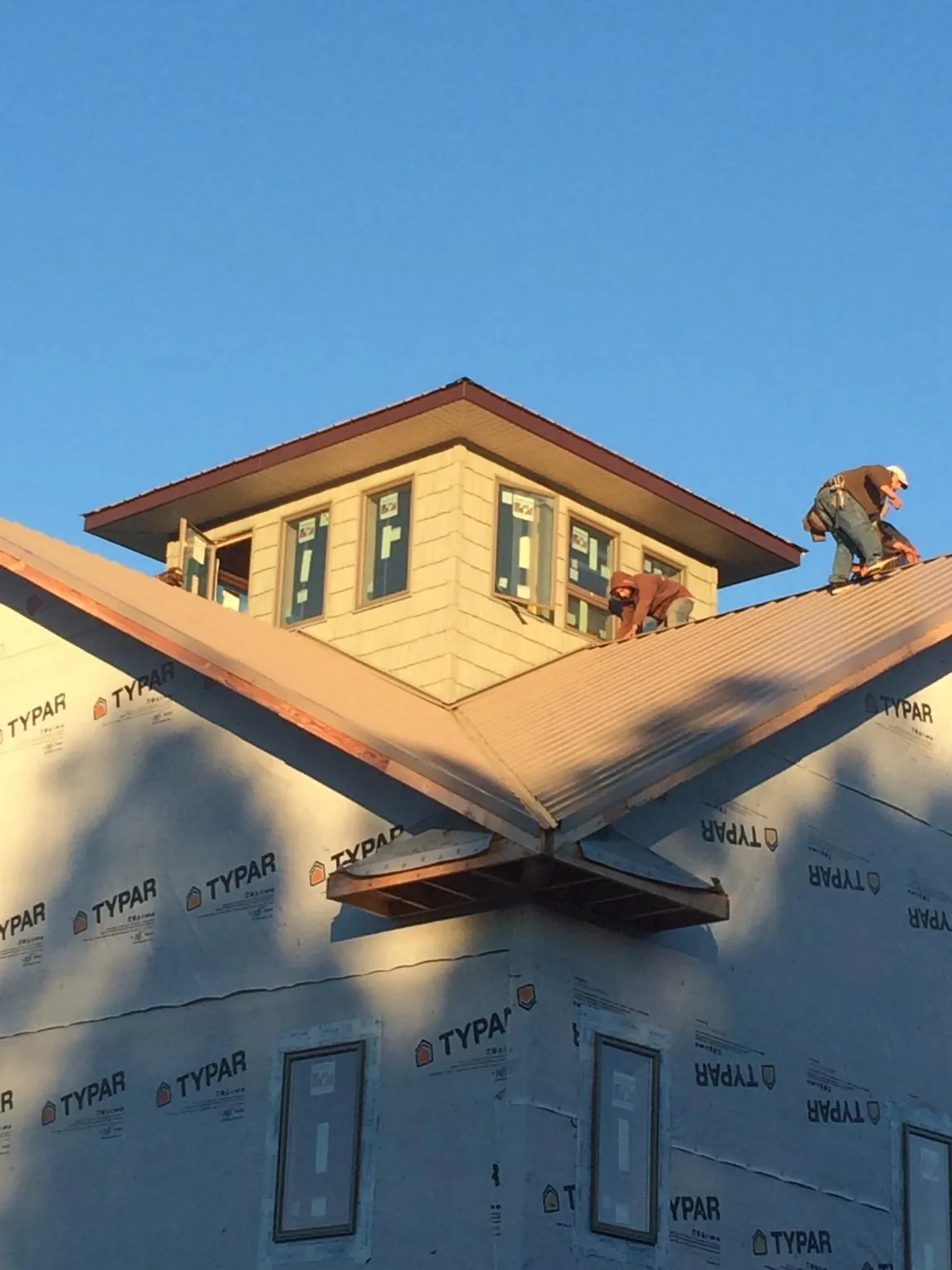 Roofers working around a rooftop cupola on a new metal roof at sunset — Roof Waterproofing in Bovey by Roofing Brothers